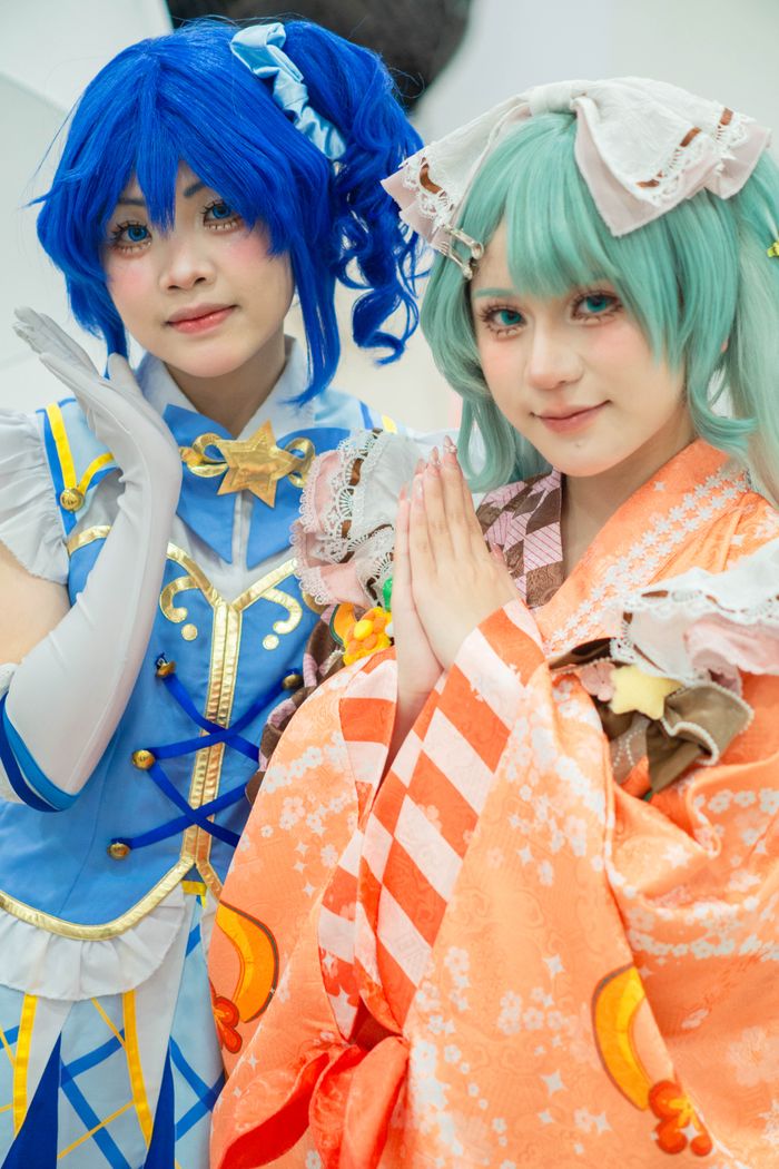 Two individuals in vibrant blue and orange cosplay costumes with intricate details.
