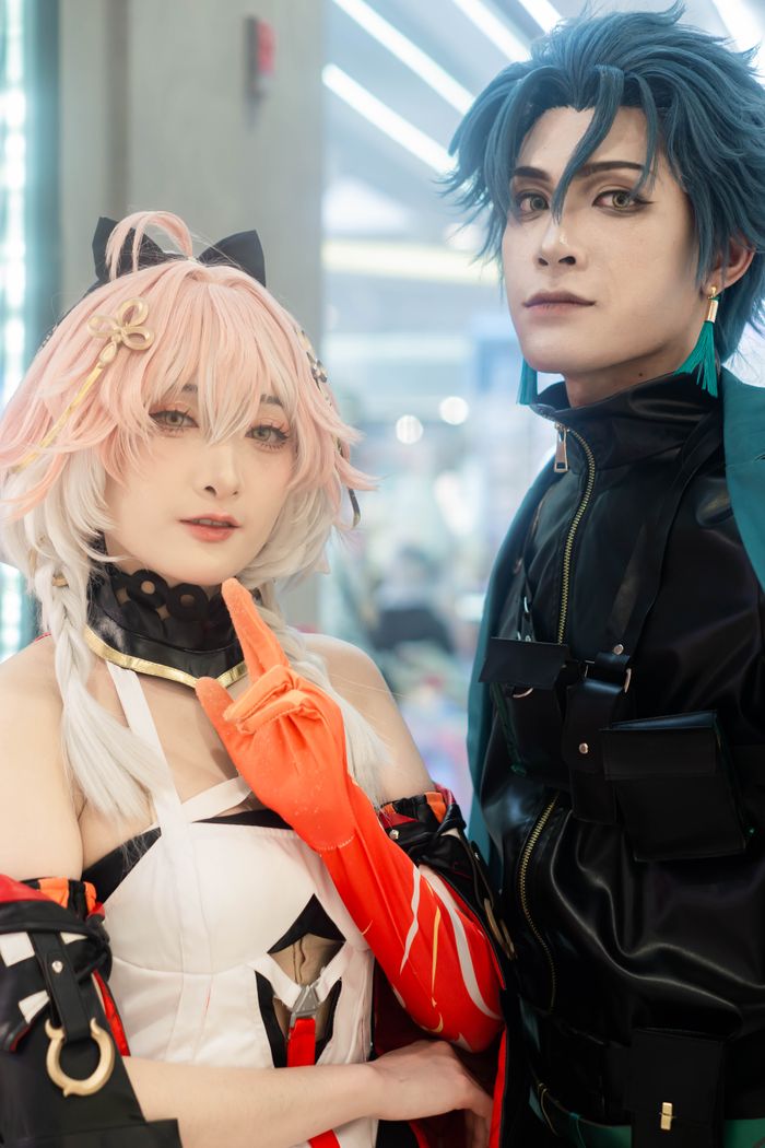 services-01 Two adults dressed in elaborate anime cosplay costumes pose indoors under bright lighting.