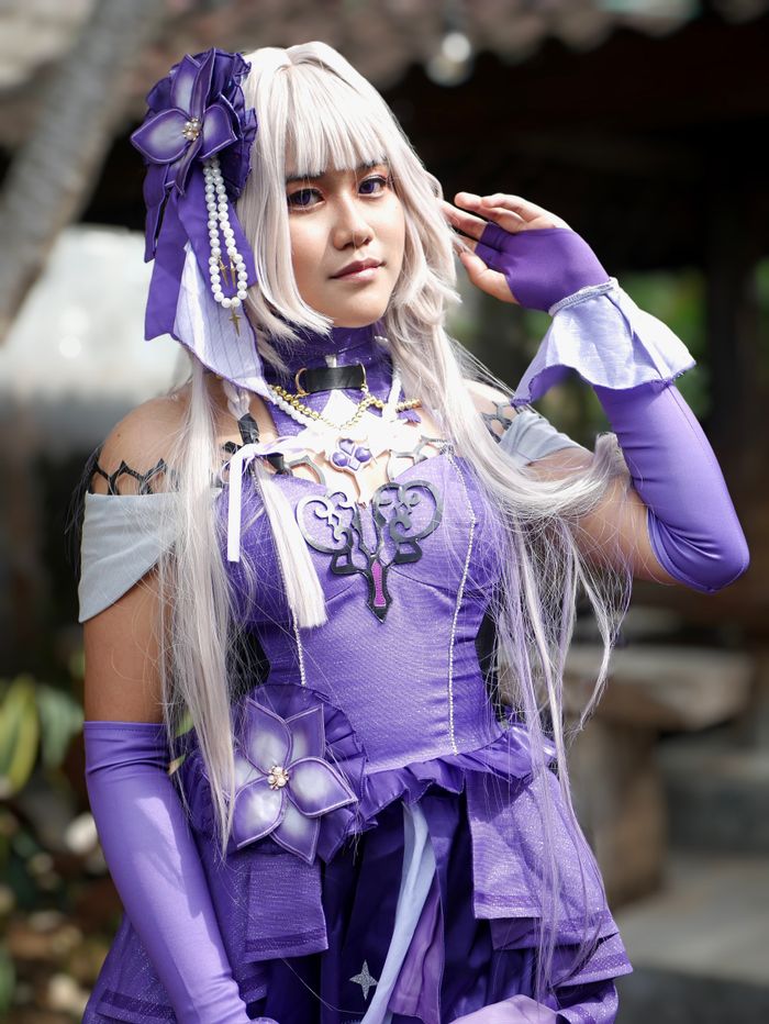 Close-up portrait of a woman in elaborate purple anime cosplay costume outdoors.
