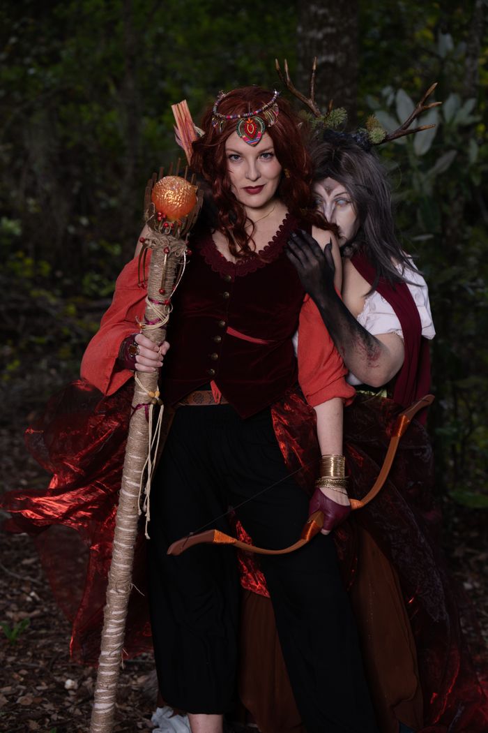 services-01 Two adults in elaborate fantasy costumes pose in a forest setting, creating a dramatic and mystical scene.